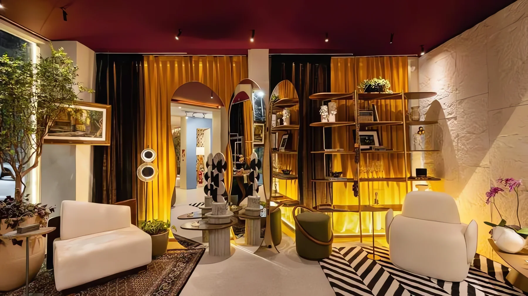 Ambiente da Mostra Home 2024 com teto bordô, cortinas douradas, estante curva e poltronas brancas sobre tapete listrado